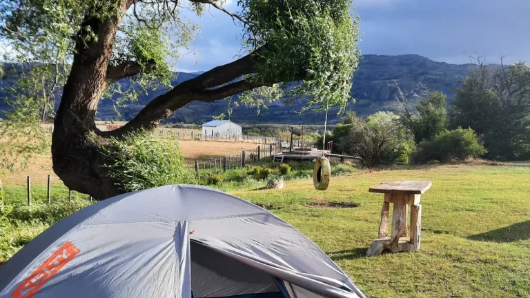 Carpa armada en un sitio de camping con praderas y cerros al fondo, en los alrededores de Puerto Varas