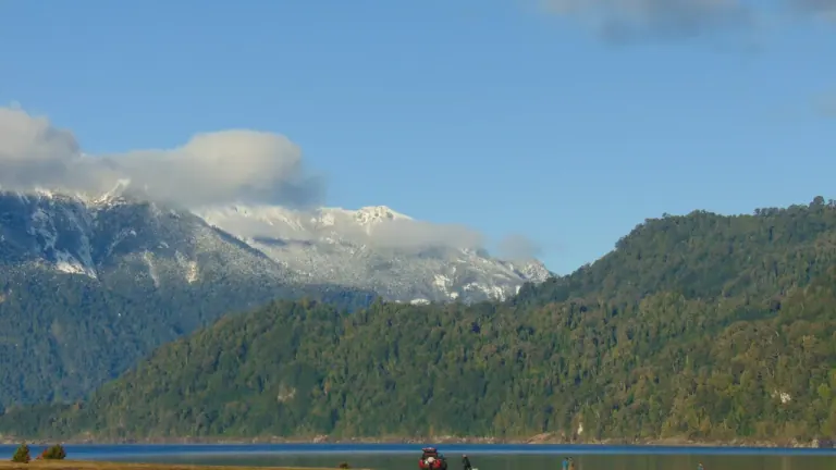 Cerros con bosque nativo y cumbres nevadas sobre la orilla del lago Chapo, en la comuna de Puerto Montt