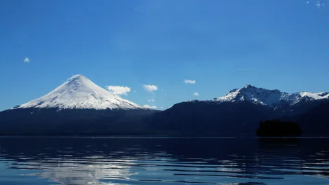 El Volcán Osorno con su cono nevado reflejado en las aguas del lago, bajo un cielo despejado