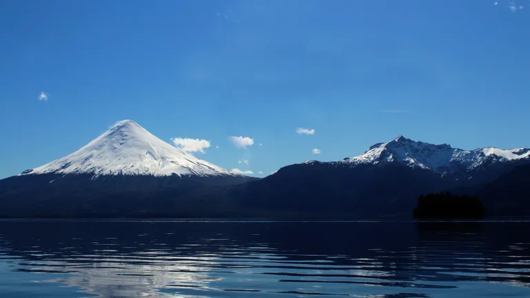 El Volcán Osorno con su cono nevado reflejado en las aguas del lago, bajo un cielo despejado